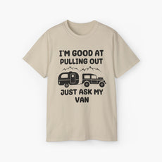 Sand color t-shirt with humorous text 'I'm good at pulling out, just ask my van,' featuring an image of a truck pulling a camping van, set against mountains on a plain background.