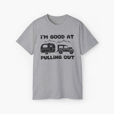 Grey t-shirt with humorous text 'I'm good at pulling out' featuring an image of a truck pulling a camping van, set against mountains on a plain background.