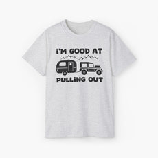 Light grey t-shirt with humorous text 'I'm good at pulling out' featuring an image of a truck pulling a camping van, set against mountains on a plain background.