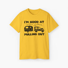 Yellow t-shirt with humorous text 'I'm good at pulling out' featuring an image of a truck pulling a camping van, set against mountains on a plain background.