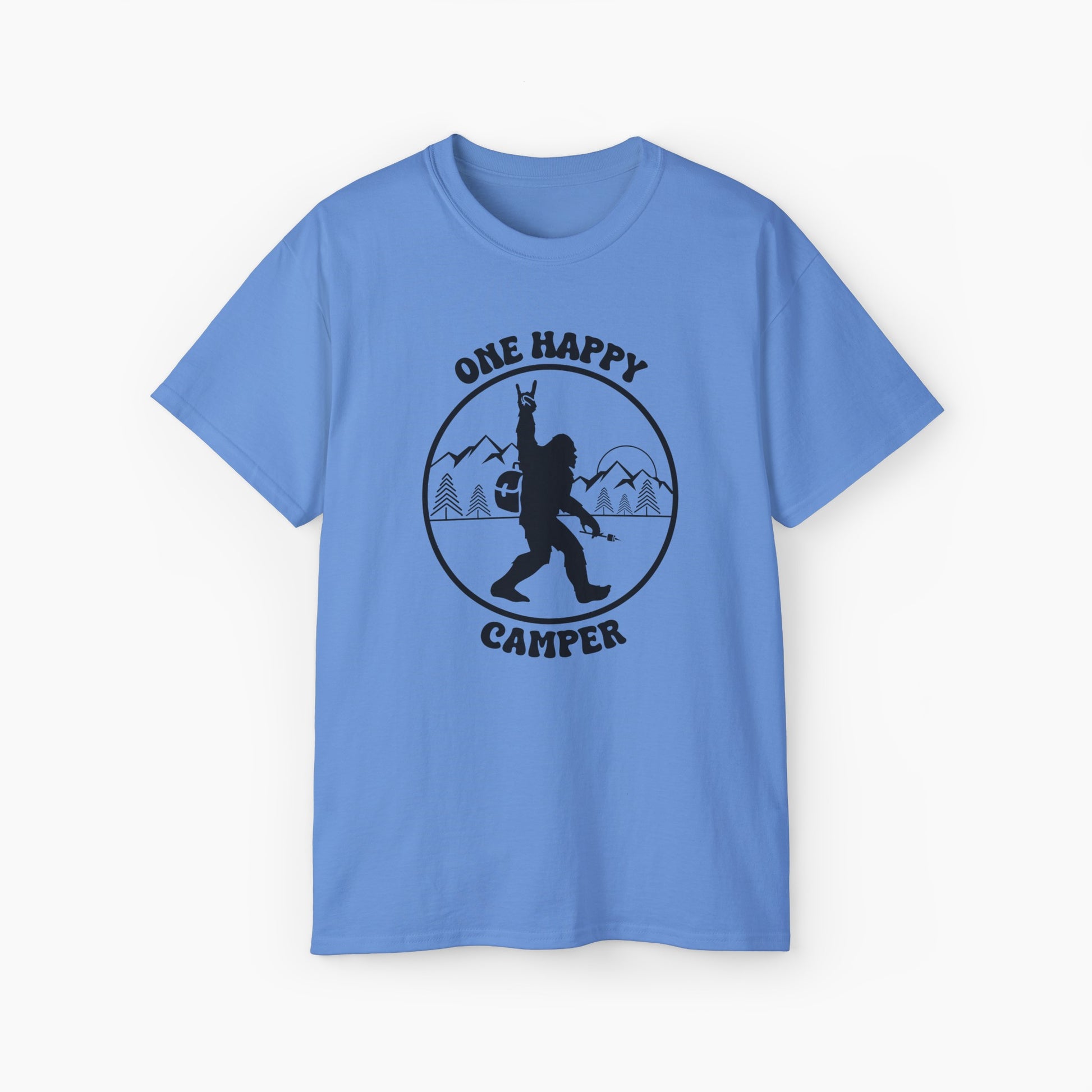 Light blue color t-shirt with 'One Happy Camper' text, featuring Bigfoot making a peace sign, set against a subtle background of trees and mountains.