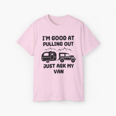 Light pink t-shirt with humorous text 'I'm good at pulling out, just ask my van,' featuring an image of a truck pulling a camping van, set against mountains on a plain background.