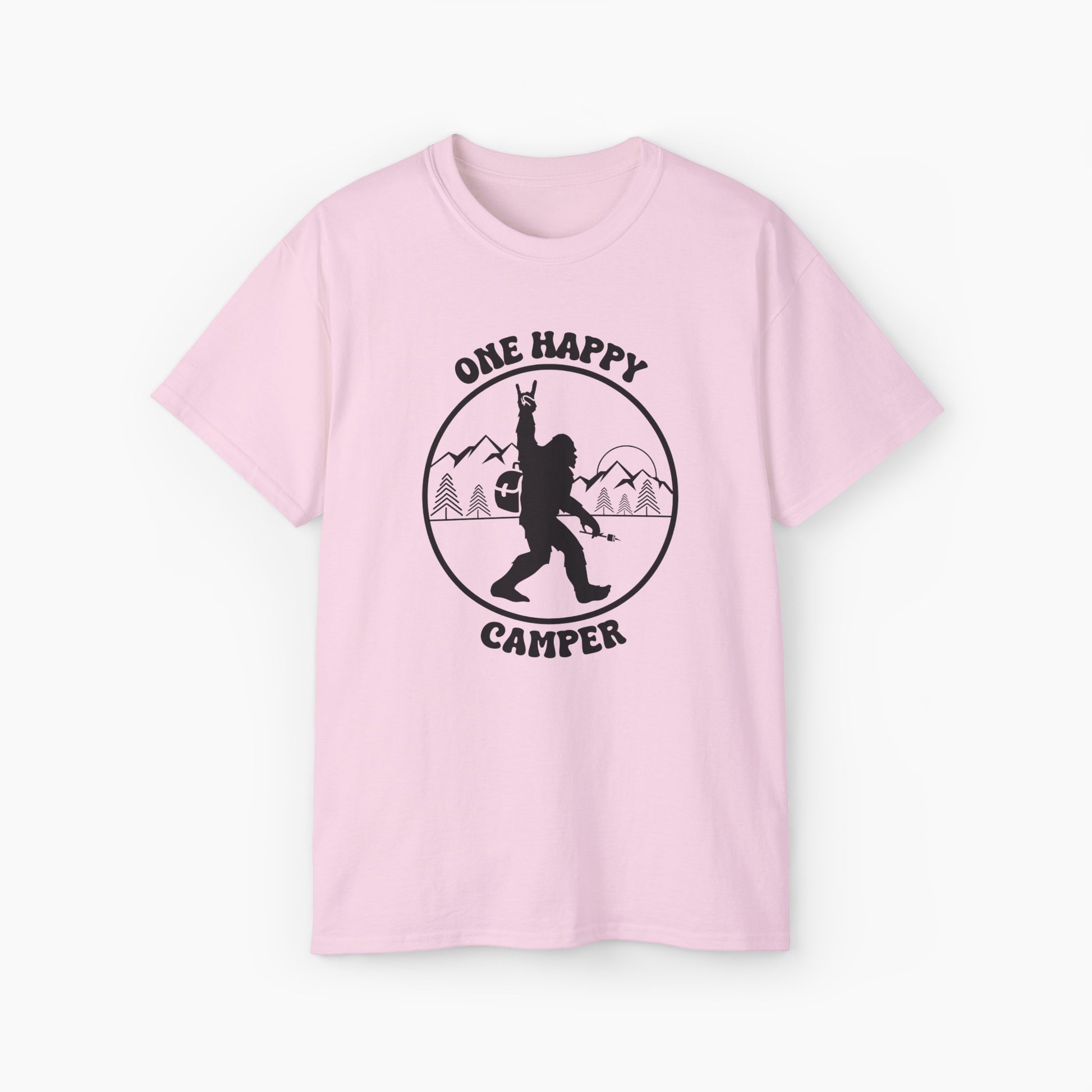 Light pink t-shirt with 'One Happy Camper' text, featuring Bigfoot making a peace sign, set against a subtle background of trees and mountains.