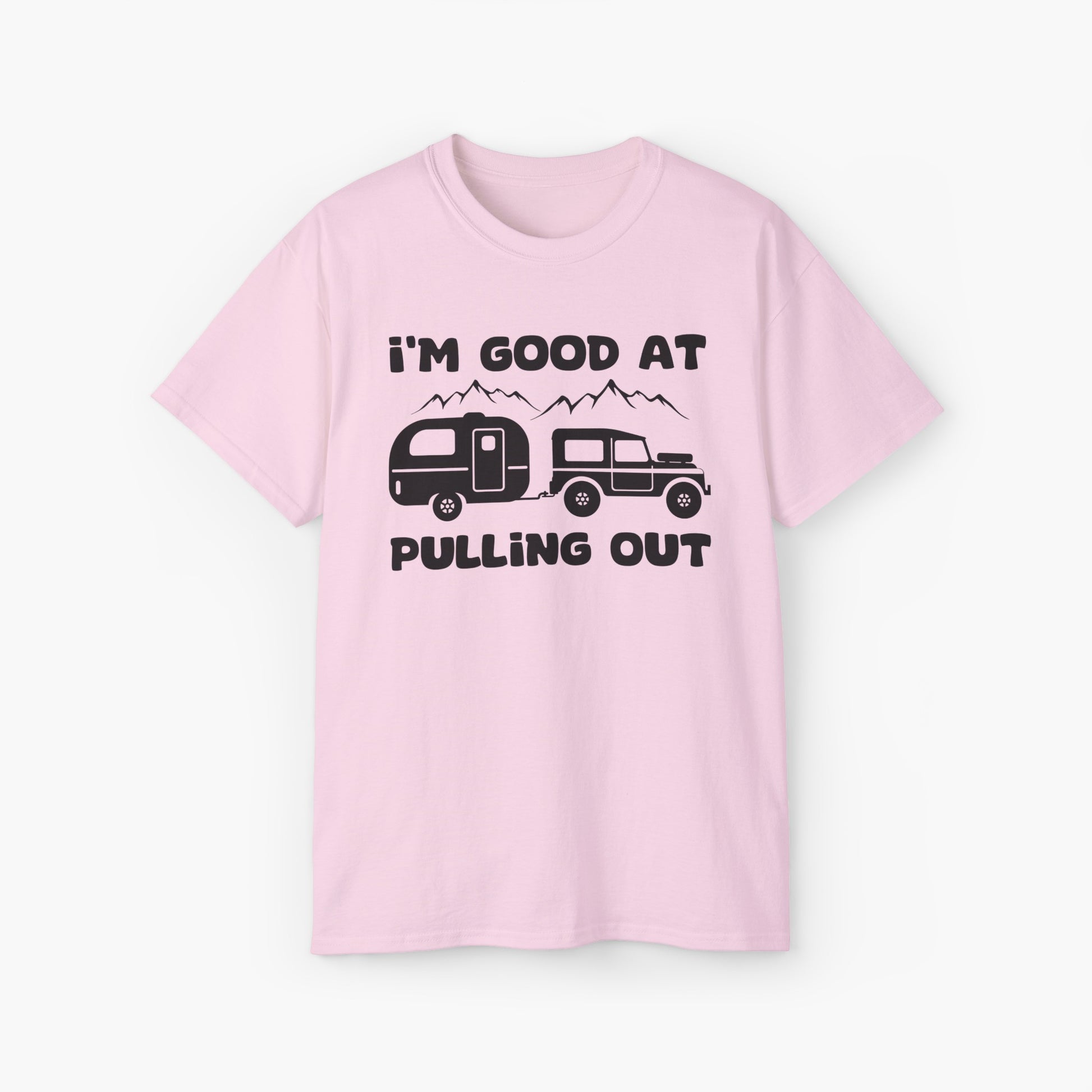 Light pink t-shirt with humorous text 'I'm good at pulling out' featuring an image of a truck pulling a camping van, set against mountains on a plain background.