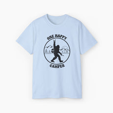 Light blue t-shirt with 'One Happy Camper' text, featuring Bigfoot making a peace sign, set against a subtle background of trees and mountains.