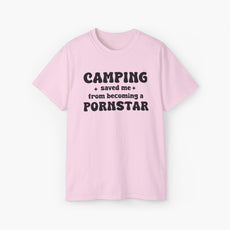 Light pink t-shirt with the bold statement 'Camping saved me from becoming a pornstar,' embellished with stars on a plain background.