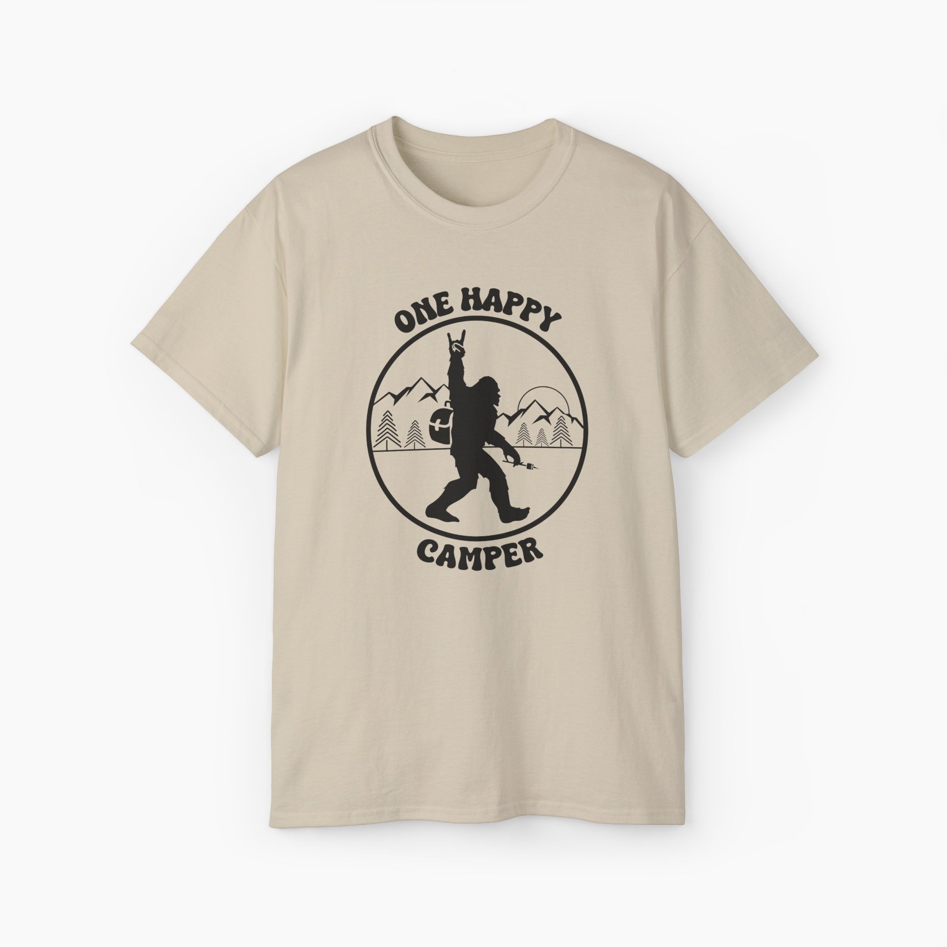 Sand color t-shirt with 'One Happy Camper' text, featuring Bigfoot making a peace sign, set against a subtle background of trees and mountains.