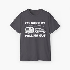 Dark grey t-shirt with humorous text 'I'm good at pulling out' featuring an image of a truck pulling a camping van, set against mountains on a plain background.