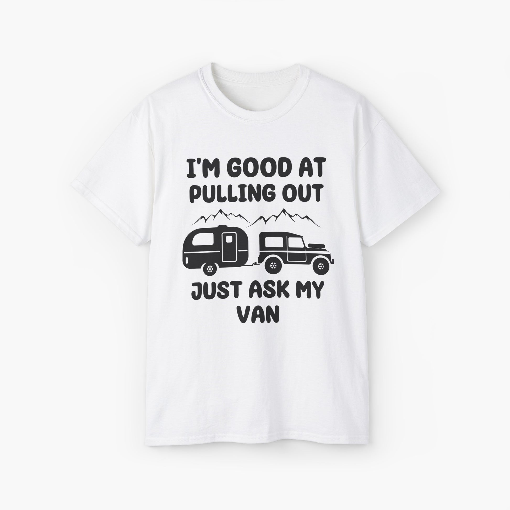 White t-shirt with humorous text 'I'm good at pulling out, just ask my van,' featuring an image of a truck pulling a camping van, set against mountains on a plain background.