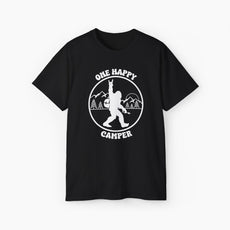 Black t-shirt with 'One Happy Camper' text, featuring Bigfoot making a peace sign, set against a subtle background of trees and mountains.