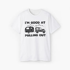 White t-shirt with humorous text 'I'm good at pulling out' featuring an image of a truck pulling a camping van, set against mountains on a plain background.