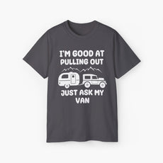 Dark grey t-shirt with humorous text 'I'm good at pulling out, just ask my van,' featuring an image of a truck pulling a camping van, set against mountains on a plain background.