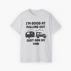 Light grey t-shirt with humorous text 'I'm good at pulling out, just ask my van,' featuring an image of a truck pulling a camping van, set against mountains on a plain background.