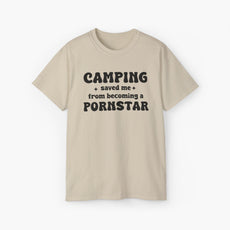 Sand color t-shirt with the bold statement 'Camping saved me from becoming a pornstar,' embellished with stars on a plain background.