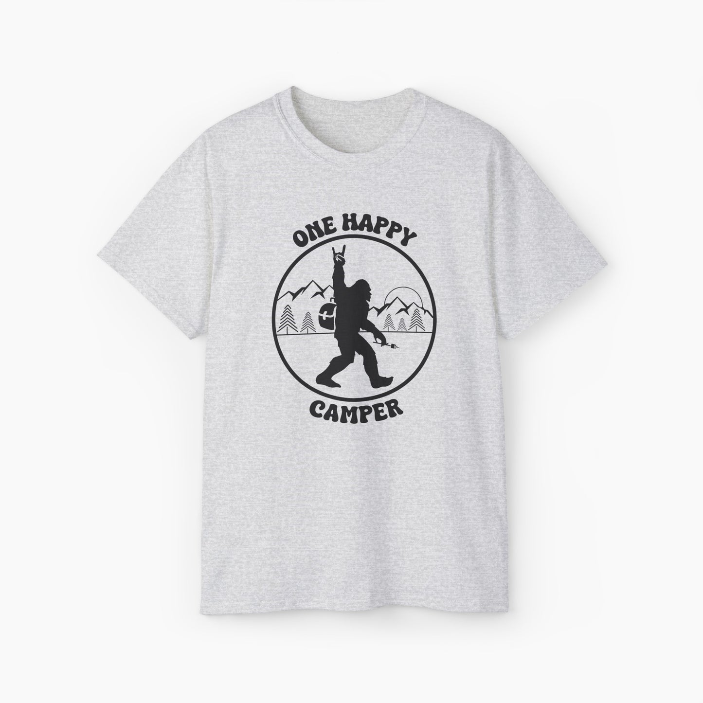 Light grey t-shirt with 'One Happy Camper' text, featuring Bigfoot making a peace sign, set against a subtle background of trees and mountains.