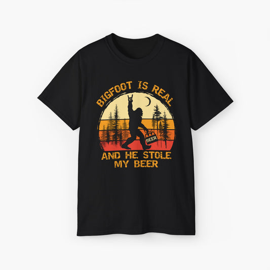 Black t-shirt with the text 'Bigfoot is real and he stole my beer,' featuring a Bigfoot holding a beer on a plain background.