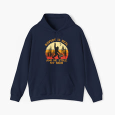 Dark blue unisex hoodie with the text 'Bigfoot is real and he stole my beer,' featuring a Bigfoot holding a beer on a plain background.
